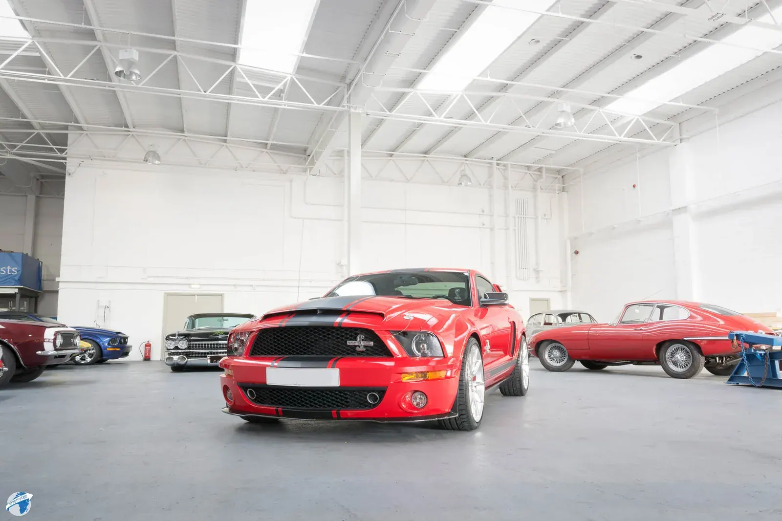 Red Shelby Super Snake Mustang with black stripes in the ShipMyCar workshop