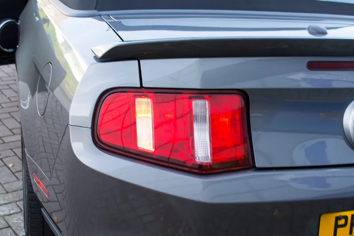 Rear light on a silver 2011 Mustang showing an illuminated section within the converted cluster