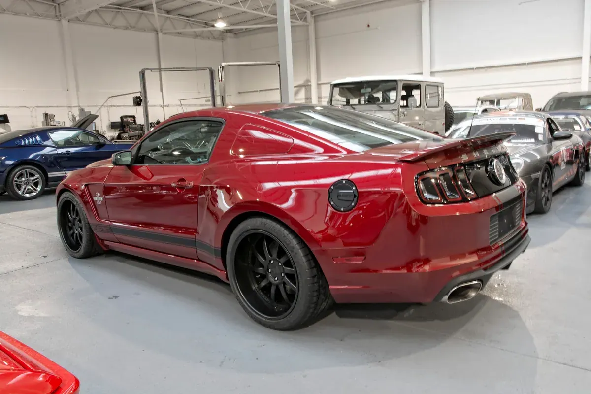 Rear quarter of a red 2014 Shelby Super Snake in the ShipMyCar workshop