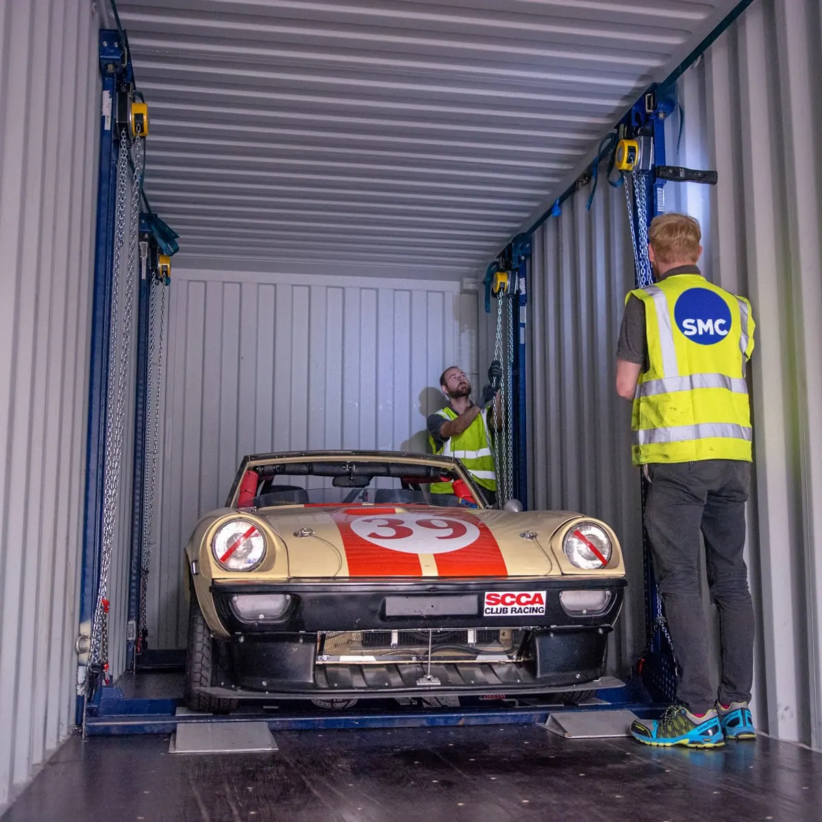 ShipMyCar team securing a race car inside a shipping container