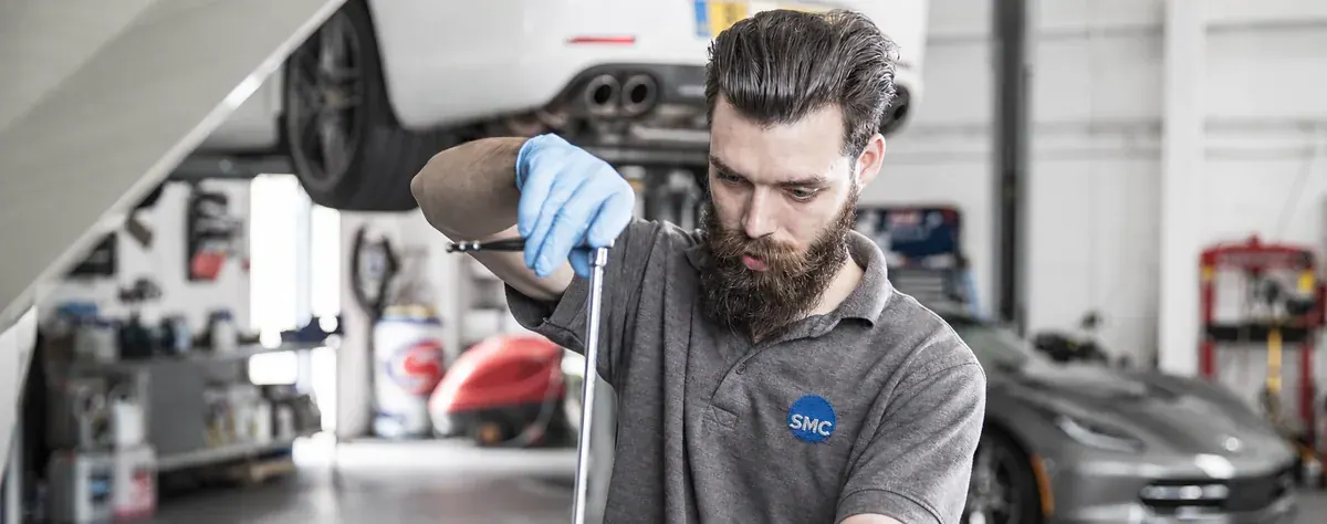 ShipMyCar technician wearing gloves and working on a car in the workshop
